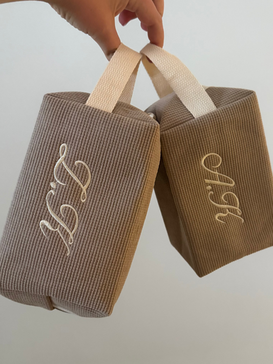Two brown corduroy bags with monogrammed initials on a plain background